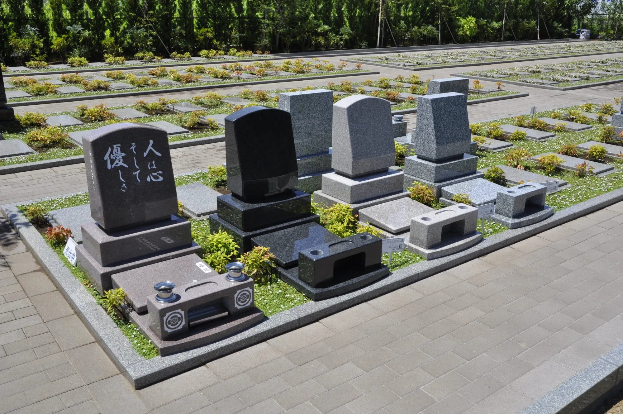 植栽に囲まれた色違いの洋型墓石