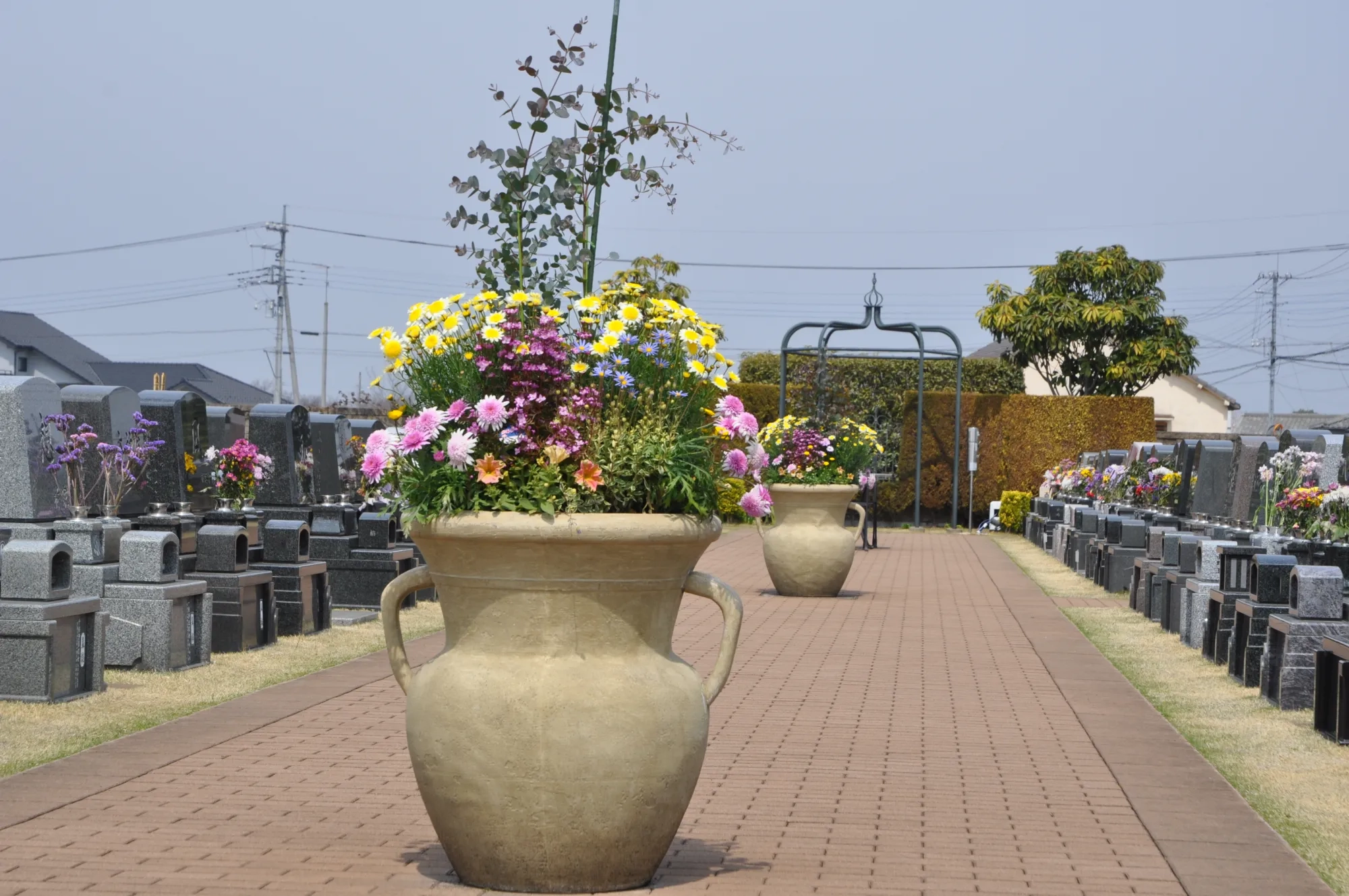 花を活けた石製の大鉢が並ぶレンガ敷きの小径
